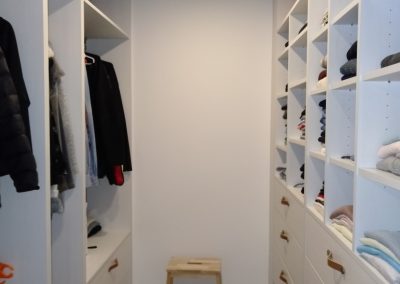 Vestidor formando un pasillo con armarios de color madera blanca llegan a techo